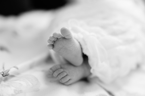 A black and white close-up of newborn baby feet on top of each other.