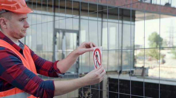 istock Foreman mounting prohibition signage on chain-link fencing on building site 2138293733