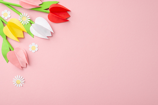 Homenaje DIY a las madres. Instantánea desde la vista superior de un ramo de tulipanes y manzanillas de origami sobre un fondo rosa suave, con espacio para contenido textual o anuncios photo