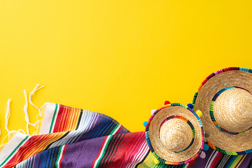 Cinco de Mayo spread. Top-view photograph capturing thematic elements: miniature sombreros, a beautifully designed multihued serape on a canary yellow backdrop