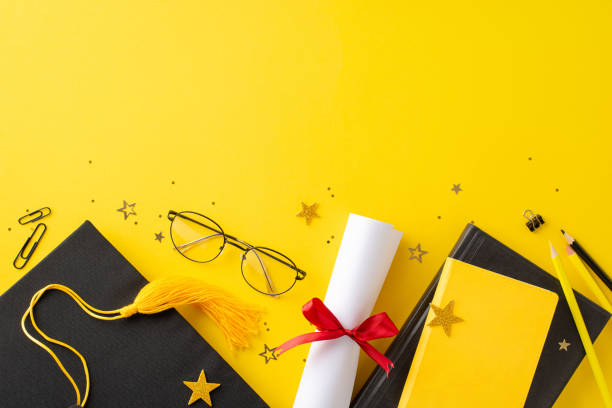 istock Dynamic top view arrangement featuring graduation cap, diploma, stationery, books, confetti on yellow backdrop, compelling image for conveying graduation excitement or advertising educational offering 2138303384