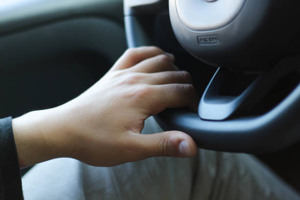 Hands on the steering wheel. The kid is holding the steering wheel of the car. Soft focus