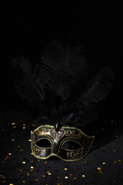 istock Carnival gold mask with feathers and confetties on black background. 2138317111