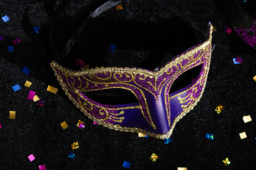 Carnival mask with confetties on black background.