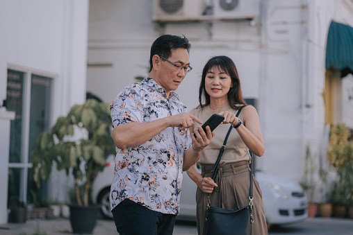 Asian Chinese senior couple tourist searching location with mobile app GPS in Penang Island