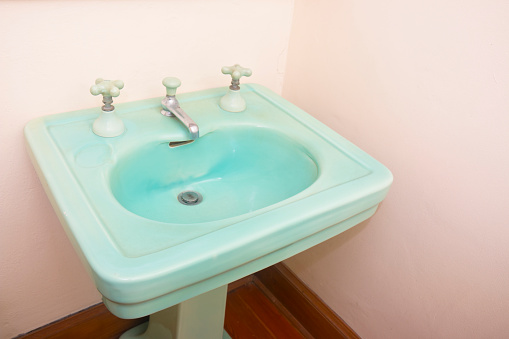 Old antique turquoise sink with taps for cold and hot water.