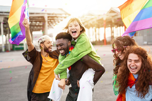 Young diverse alternative friends having fun with LGBT rainbow flags - Inclusive friendly gay community