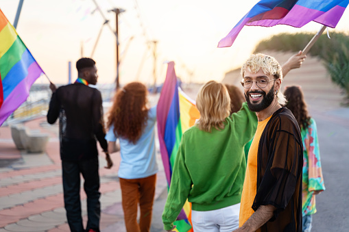 Portrait of smiling gay man with beard together with group of friends celebrating Lgtb pride festival parade