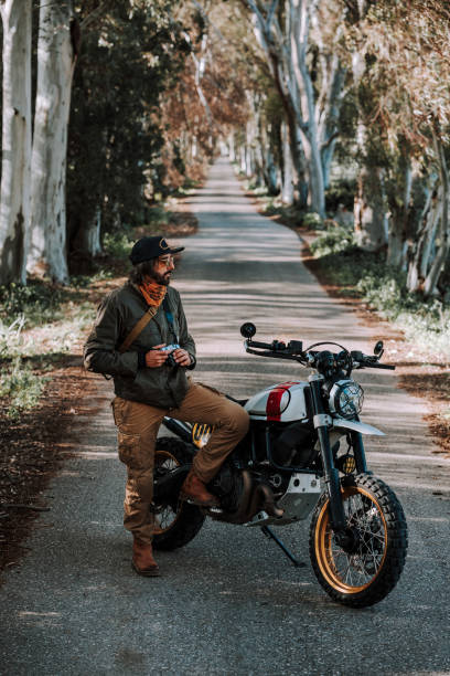 istock a man sitting on the handlebars of his motorcycle 2138421767