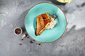 Pan-seared halibut in Unagi sauce with creamy rice served on a turquoise dish, against a textured gray background