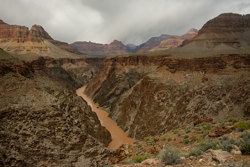 Muddy Colorado River Cuts Through The Grand Canyon Covered In Dark Clouds During Spring Storm