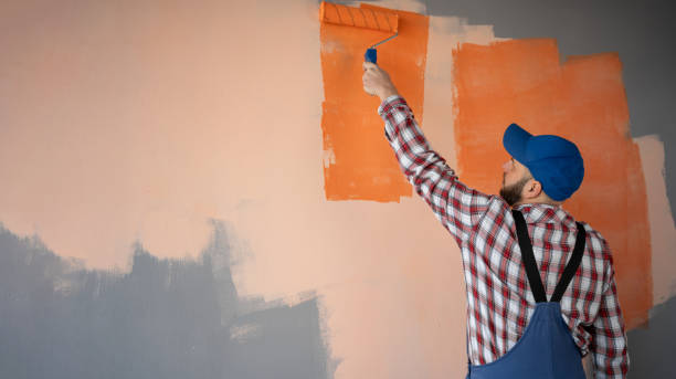 istock Building contractor in blue cap painting wall with roller brush. Construction worker renovating house. 2138435671