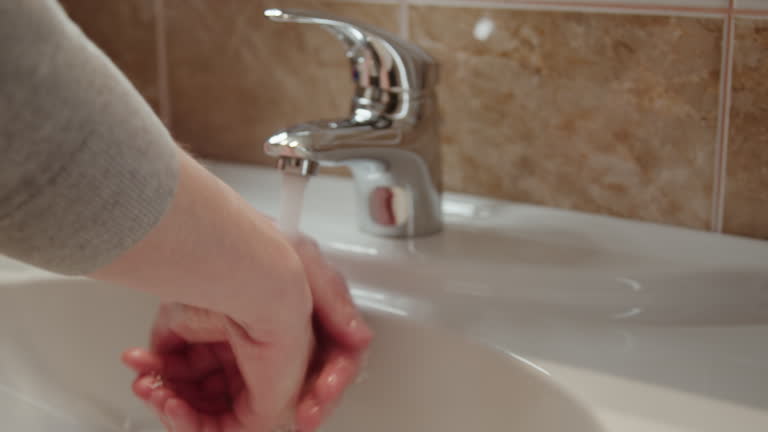 Person meticulously washes their hands under flowing water in close-up recognizing pivotal role of hygiene in washes hands purity of skin preventing spread of illness. Person washes hands in sink.