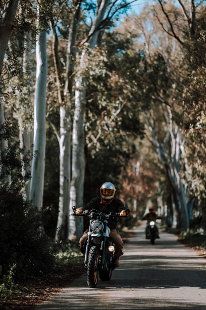 istock a person riding a motorcycle down a tree lined street during the day 2138451393