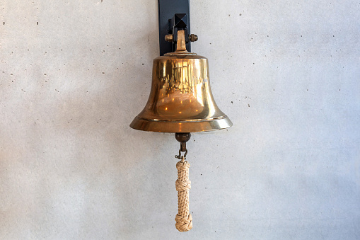 Brass bell on a gray wall indoors.