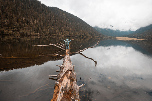 Woman walking on a one plank bridge in high altitude mountains