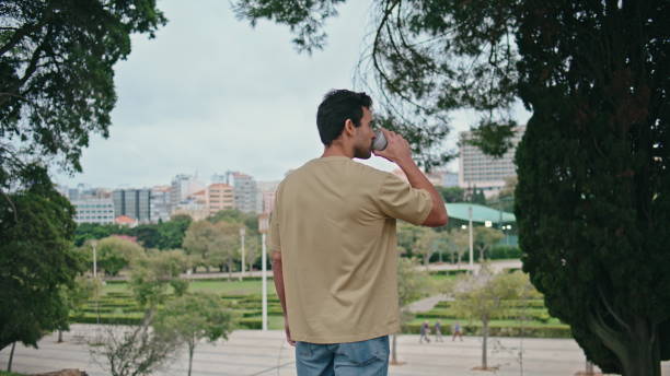istock Tranquil man drinking coffee in green park back view. Relaxed guy enjoy beverage 2138513384