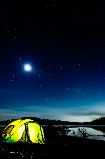 Illuminated tent lakeside under the stars