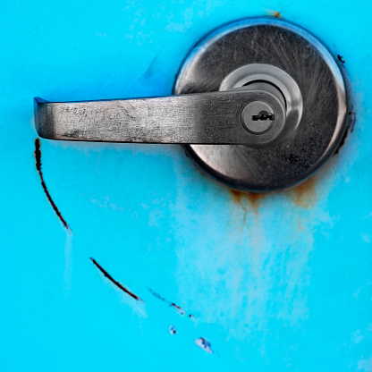 Metal handle with round scratch mark on blue metal door with lock for security