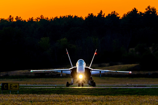 Gatineau, Quebec – September 15, 2023: The Royal Canadian Air Force FA-18 is taxiing off of the runway at the AeroGatineau Air Show evening performance from the FA-18 Demo Team.  The sun is setting not only on the airshow but on the RCAF FA-18 as the replacement F-35s are now on the radar screen.