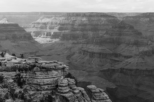 Panoramic photo of Grand Canyon in Arizona whit a lone man at the edge of the cliff with cloudy weather in black and white
