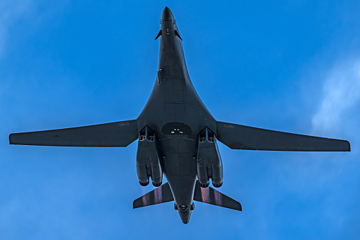 Las Vegas, NV – August 2, 2023 A Rockwell B-1B Lancer is captured from below against varying skies, showcasing its extended landing gear and intricate underbelly. The B-1B's design, with swept-back wings is designed for long-range missions and high-speed flying.  The afterburners are lit on takeoff for several images at sunset as it departs the Las Vegas, Nellis Air Force Base for a nighttime combat training mission as part of the annual Red Flag exercises conducted at Nellis.