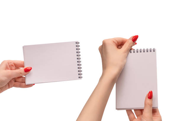 A notebook with empty white paper in woman hands with red nails. Copy space.