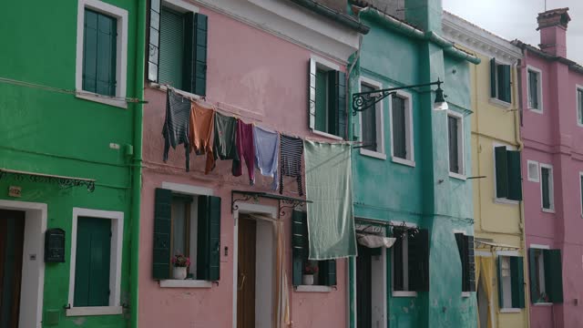 Laundry hangs across a street in colorful pastel Burano, Italy