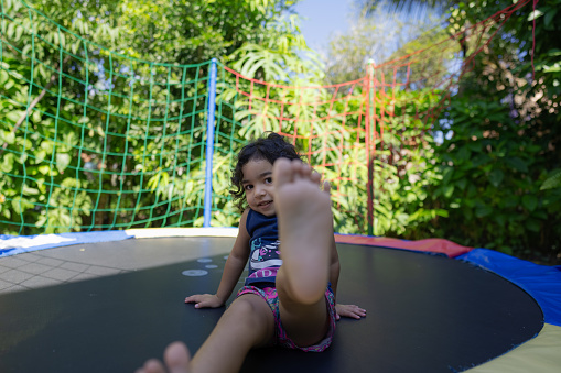 Little girl enjoys jumping on a trampoline outdoors.
