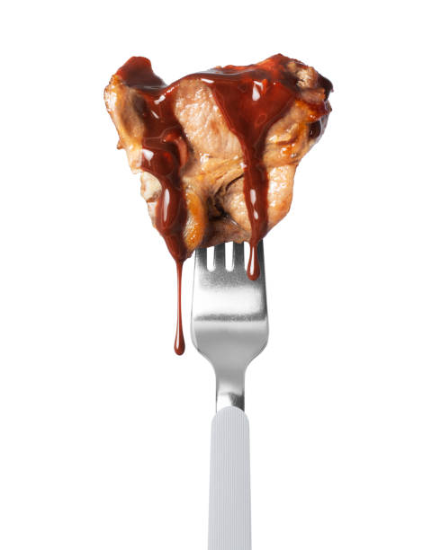 istock Fried beef steak poured with sauce on a fork close up isolated on a white background 2138637695