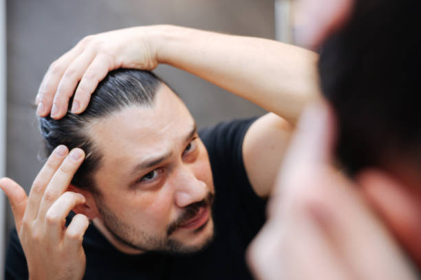istock Man in front of mirrror looking at his hair 2138654508
