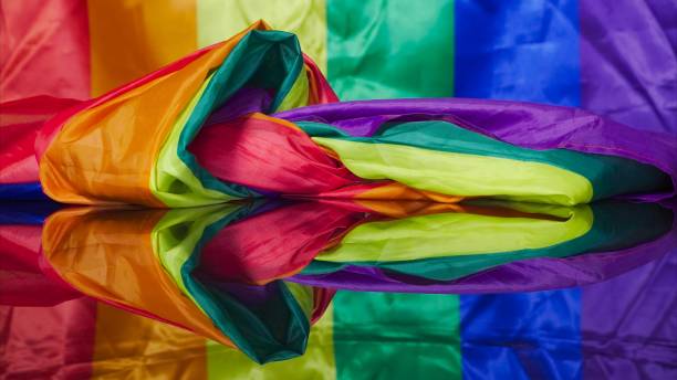 istock Rainbow fabric located in abstract shape on reflective plane and gay flag on background 2138666023