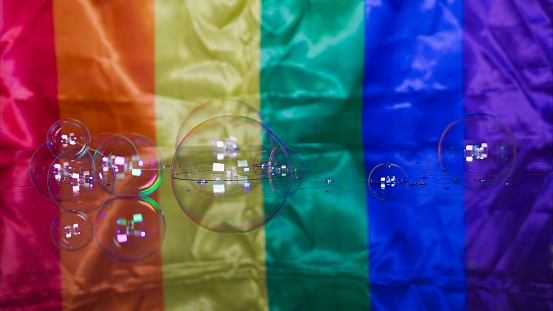Soap bubbles on rainbow glass surface with Gay and LGBT flag in the background