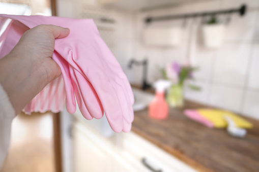 housewife holds pair of pink rubber household gloves for protecting hands during cleaning tasks in kitchen and other rooms, Spring Clean, Fresh Start, Maintaining Clean Home