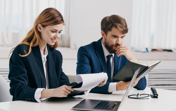 istock business man and woman sit at the table with open laptop in office and notepad documents model 2138694770