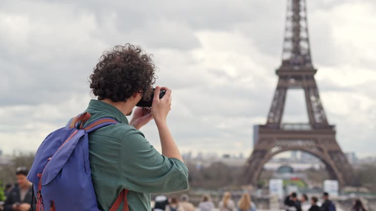 Adult Male Tourist Taking Pictures Of Eiffel Tower With A Camera In Paris, France