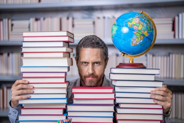 istock Knowledge and education concept. school teacher with book in classroom. teacher in classroom. Teachers Day. Tutor at classroom. Man geographer with books in classroom. Page turner 2138699490