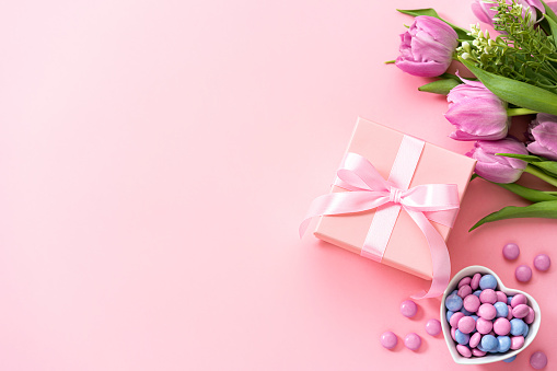 Mother's Day design concept background with tulips, candies and gift on pink background. Copy space. High resolution 42Mp studio digital capture taken with Sony A7rII and Sony FE 90mm f2.8 macro G OSS lens