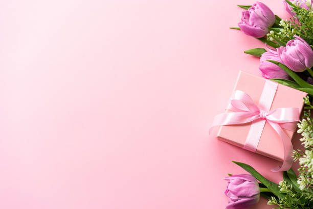 Mother's Day gift box and tulips on pink background. Copy space
