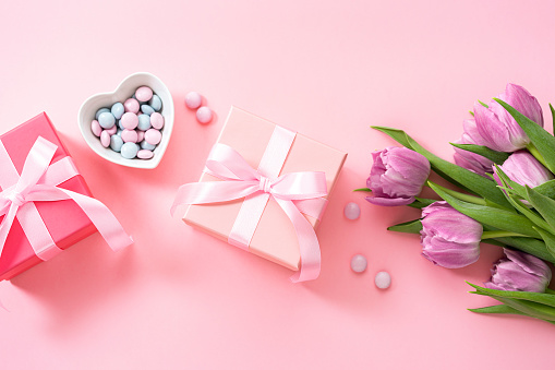 Mother's Day concept. Two gift boxes, candies and tulips on pink background. Copy space. High resolution 42Mp studio digital capture taken with Sony A7rII and Sony FE 90mm f2.8 macro G OSS lens