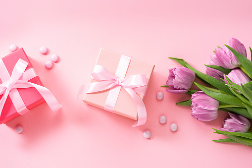 Mother's Day concept. Two gift boxes, candies and tulips on pink background. Copy space. High resolution 42Mp studio digital capture taken with Sony A7rII and Sony FE 90mm f2.8 macro G OSS lens