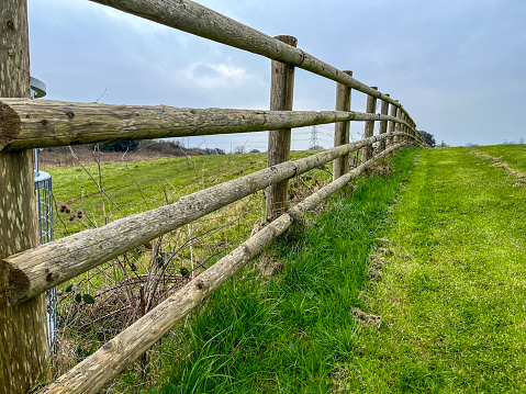The old gray wooden fence dividing the green grass field on a sunny day