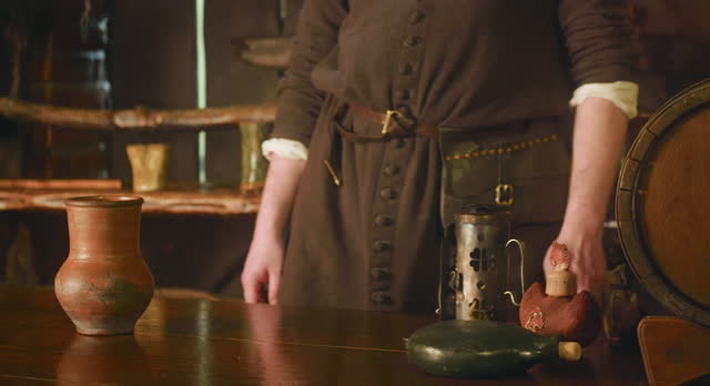 Medieval servant stands at counter in tavern