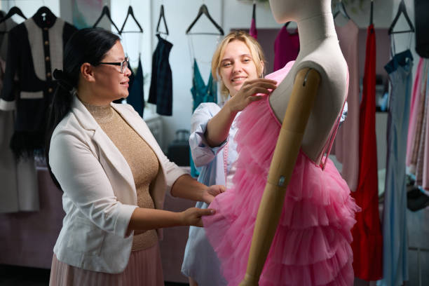 istock Two women stylists model an evening dress on a mannequin 2138752076