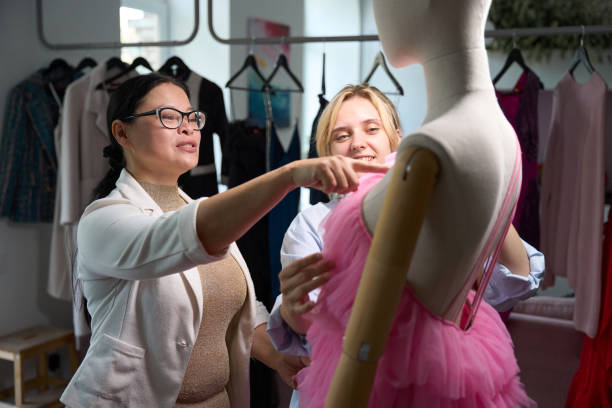 Female stylists model an evening dress on a mannequin