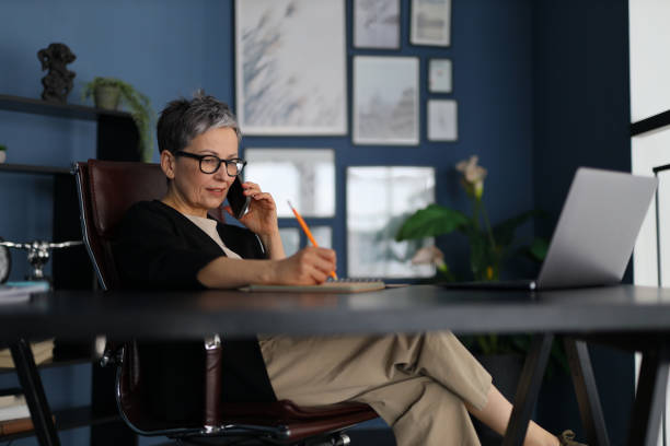 istock A mature Caucasian entrepreneur engages in a thoughtful conversation on her smartphone while working in her modern office. 2138807753