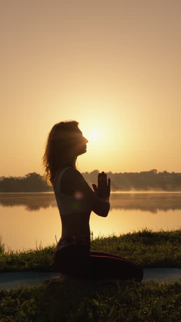 Young woman enjoying yoga exercises outdoors, feeling calm and contentment amidst natural beauty, promoting vitality and happiness.