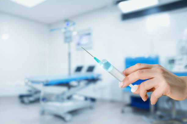Hand holding a syringe with medicine on a blurred background.