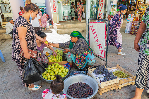 Bukhara, Uzbekistan, Central Asia. August 25, 2021. Woman selling fresh fruit at a market in Bukhara.