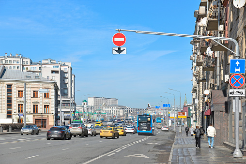 Moscow, Russia - April 3, 2024: Bolnaya Polyanka street towards the Small Kamenny Bridge with cars and buses. A pole with road signs No Entry, No stopping, Lane for route vehicles, including road sign Dedicated bus lane.
